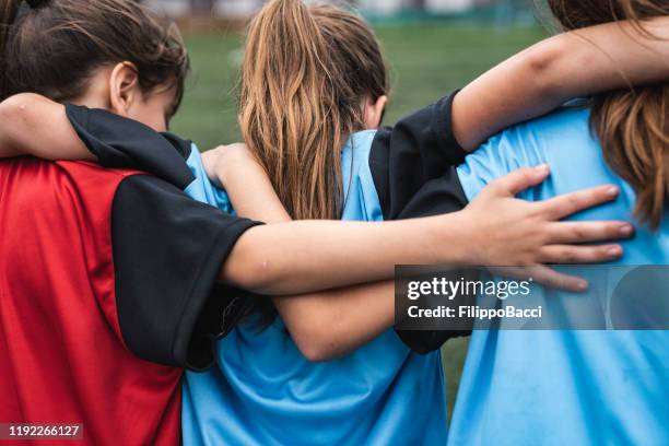 tre ragazze che si sostengono a vicenda mentre giocano a calcio - children sport foto e immagini stock