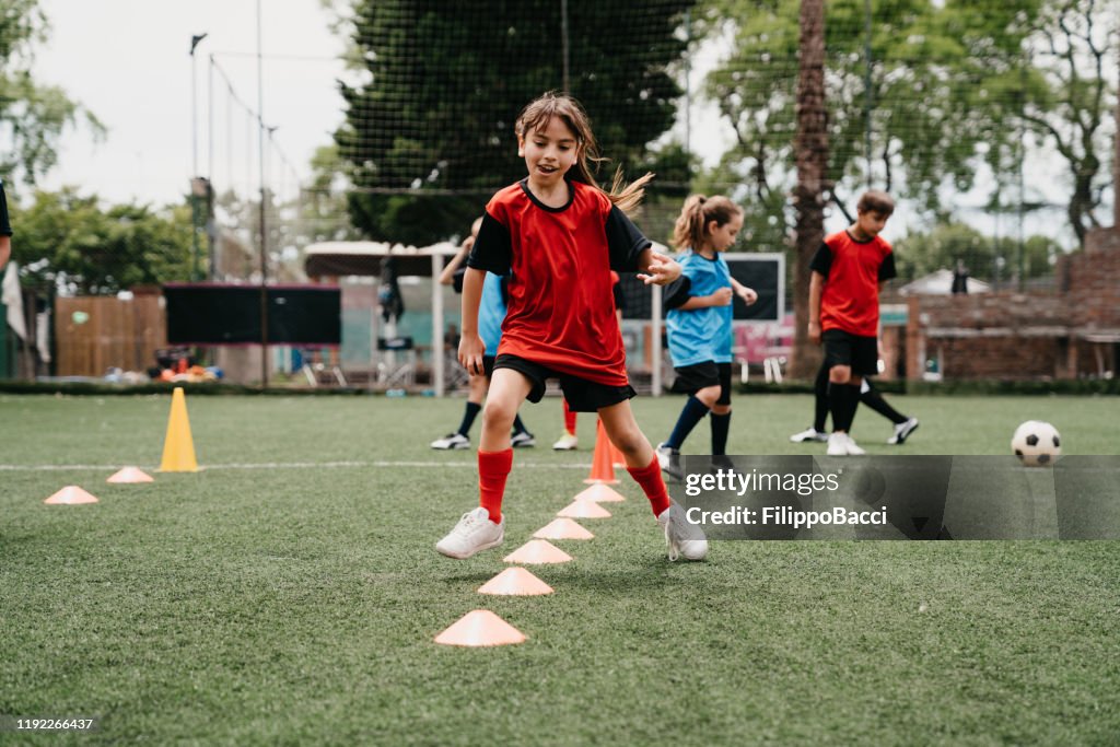 Determined girl practicing soccer drills on field