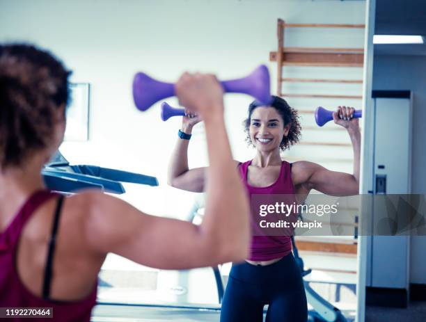 frau krafttraining mit hanteln - schulterpresse stock-fotos und bilder