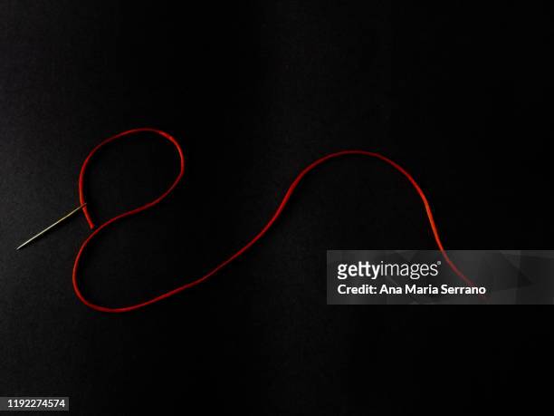sewing needle with a bright red silk thread on a black background - sewing needle stock pictures, royalty-free photos & images