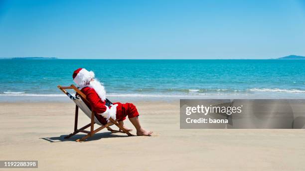 santa claus ontspannen op het strand - christmas summer stockfoto's en -beelden