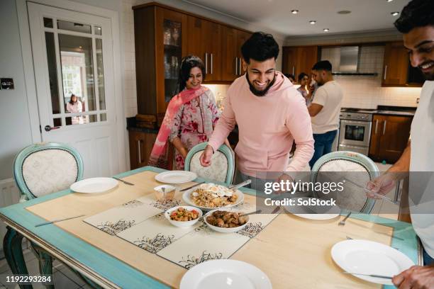 dishing out the family dinner - indian family dinner table stock pictures, royalty-free photos & images