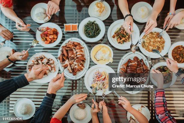 asian chinese family enjoy their home made food during chinese new year's eve reunion dinner - picking up food stock pictures, royalty-free photos & images