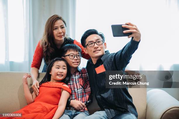 asian chinese father holding mobile phone and taking family selfie during chinese new year's eve - mom blessing son stock pictures, royalty-free photos & images