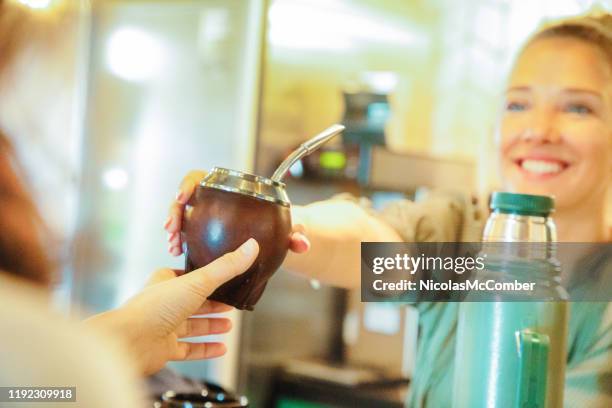 millennial blonde argentinian female worker giving mate to her friend in traditional mug - gourd stock pictures, royalty-free photos & images