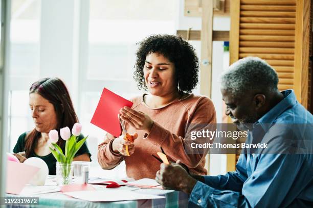 smiling woman in discussion with father and friends while cutting out valentines day card - バレンタイン　��友人 ストックフォトと画像