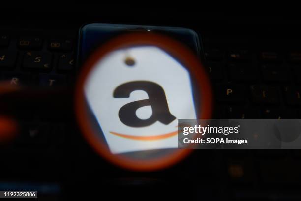 In this photo illustration an Amazon logo seen displayed on a smartphone through a magnifying glass.