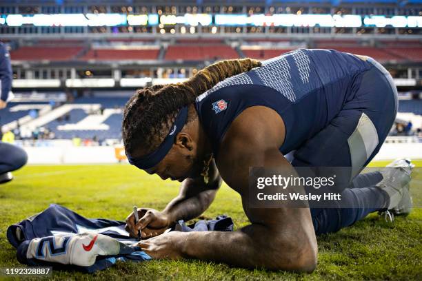 Derrick Henry of the Tennessee Titans signs his jersey after a game against the Jacksonville Jaguars at Nissan Stadium on November 24, 2019 in...