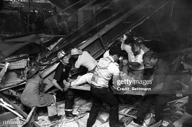 Firefighters rescue people from under a collapsed walkway in the lobby of the Hyatt Regency hotel. At least 25 people were killed and 100 injured by...