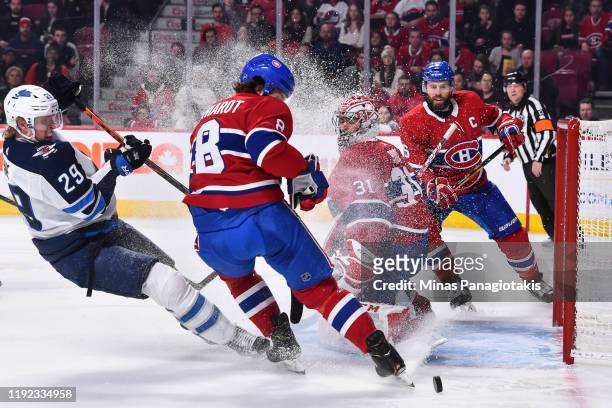 Goaltender Carey Price of the Montreal Canadiens protects the net against the puck while teammate Ben Chiarot defends against Patrik Laine of the...