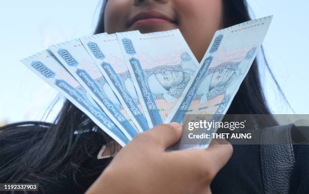 Woman holds new Myanmar kyat banknotes with a portait of the late general Aung San, outside the Myanmar Economic Bank in Naypyidaw on January 7, 2020.