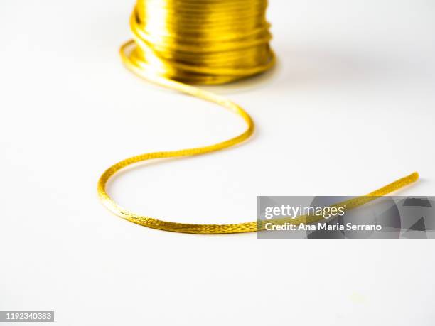 spool of bright golden silk thread on a white background - gold satin ribon stock-fotos und bilder