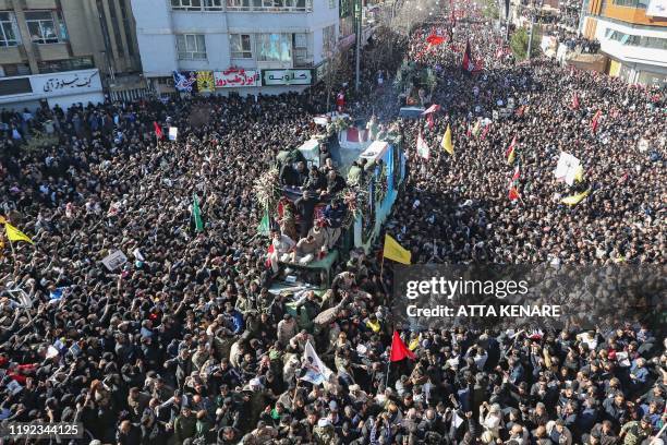 Iranian mourners gather around a vehicle carrying the coffin of slain top general Qasem Soleimani during the final stage of funeral processions, in...