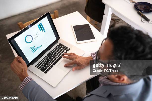 high angle view of a businessman using laptop in a restaurant - performance stock pictures, royalty-free photos & images