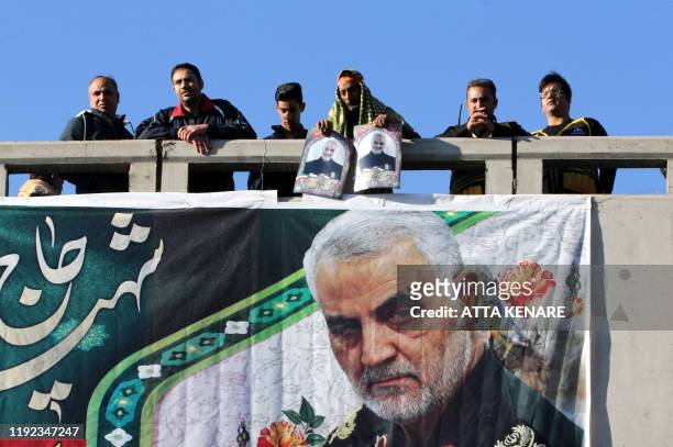 Iranian mourners stand on a bridge during the final stage of funeral processions for slain top general Qasem Soleimani, in his hometown Kerman on...