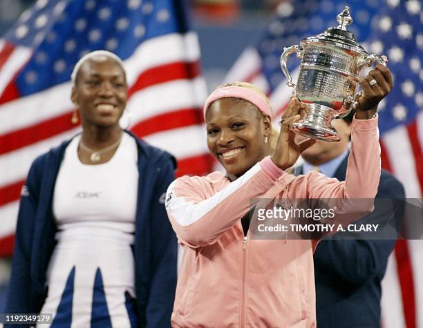 Serena Williams of the US holds up the US Open Women's Singles trophy as her sister Venus looks on at the US Open Tennis Tournament 07 September,...