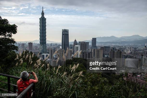 Man photographs the Taipei 101 tower, once the worlds tallest building, and the Taipei skyline from the top of Elephant Mountain on January 7, 2020...