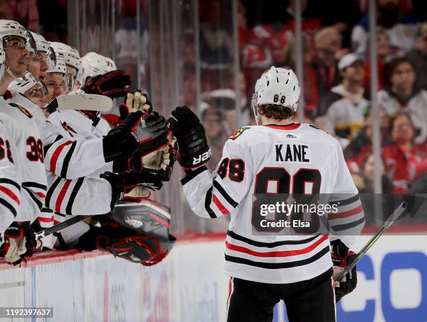 Patrick Kane of the Chicago Blackhawks is congratulated by teammates on the bench after he got the puck past Mackenzie Blackwood of the New Jersey...