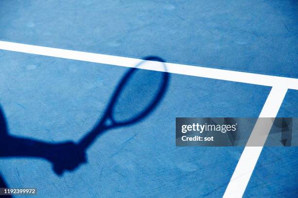 shadow of hand holding a tennis racket - racchetta da tennis foto e immagini stock