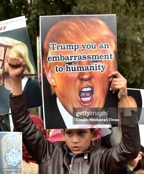 People hold placards and raise slogans during a protest against the killing of Iranian major general Qassim Soleimani, near US high commission on...