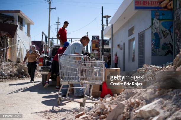 People inspect damage and help to take merchandise out of a local store after a 6.4 earthquake hit just south of the island on January 7, 2020 in...