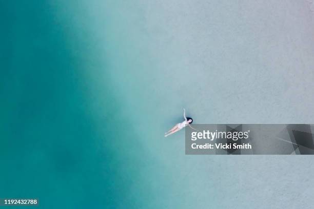 aerial view above a woman lying, floating in the shallow water of the ocean - queensland people stock pictures, royalty-free photos & images
