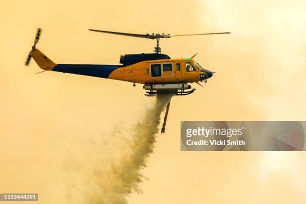 helicopter dropping water onto forest fires - emergency services australia imagens e fotografias de stock