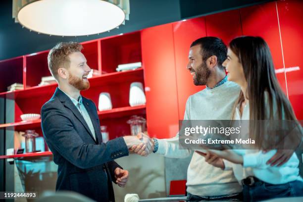young couple giving a handshake to a sales assistant in a home improvement store - loja de utensílios de cozinha imagens e fotografias de stock
