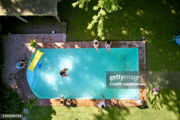 vista de ángulo alto de la familia disfrutando de la piscina del patio trasero - backyard pool fotografías e imágenes de stock