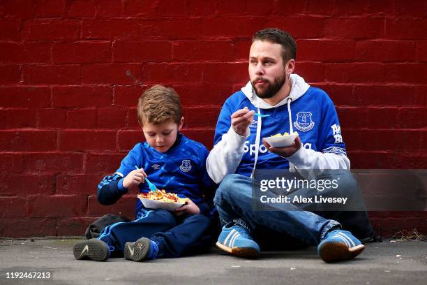 Fans wait outside the stadium while eating food ahead of the Premier League match between Everton FC and Chelsea FC at Goodison Park on December 07,...