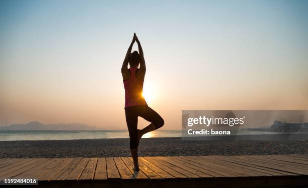 vista posteriore della donna in posa yoga in spiaggia - sunrise yoga foto e immagini stock