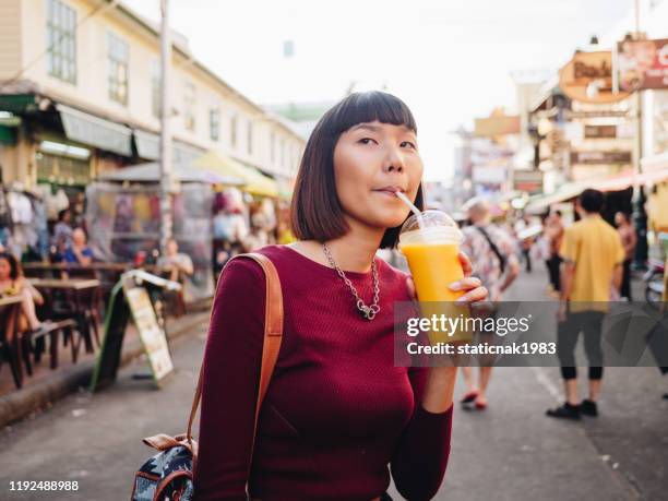 jonge vrouw genieten van mango sap in khao san road. bangkok - mango juice stockfoto's en -beelden