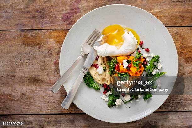 mashed pumpkin with kale, hummus, pomegranate seeds with a poached egg on toast. - eggs benedict overhead stock pictures, royalty-free photos & images