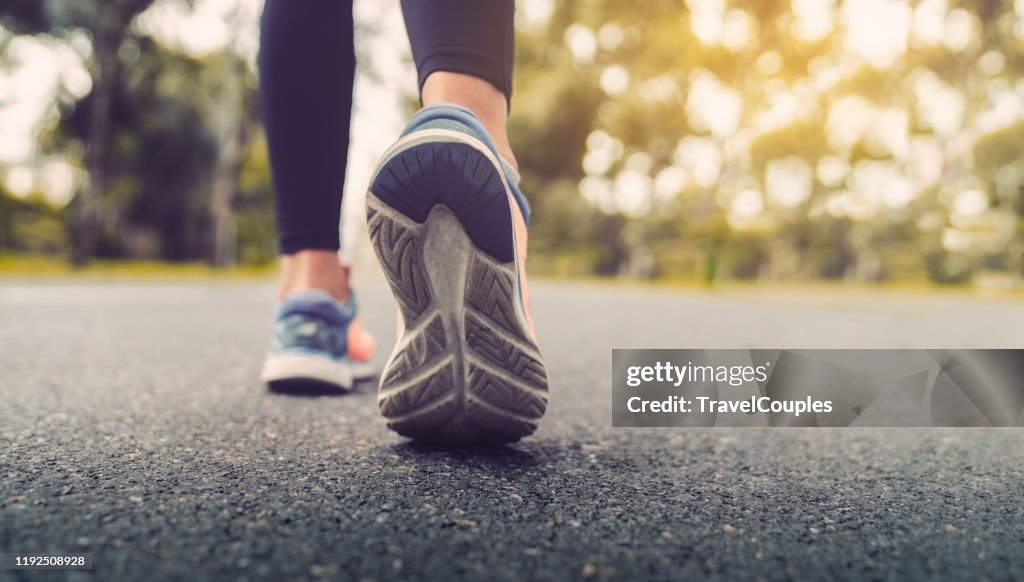 Woman feet running on road closeup on shoe. Young fitness women runner legs ready for run on the road. Sports healthy lifestyle concept.