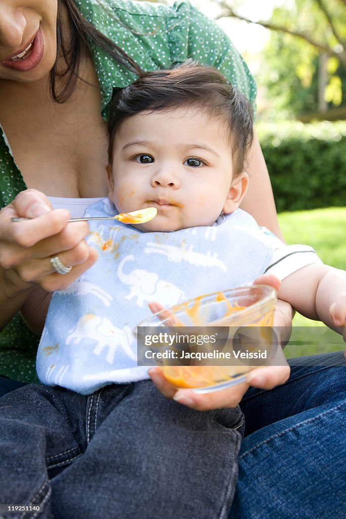 Six month old baby boy being fed by mother