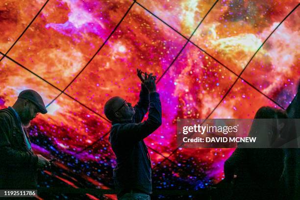 People look at panel of curved LG OLED televisions on opening day of the 2020 Consumer Electronics Show in Las Vegas, Nevada on January 7, 2020.