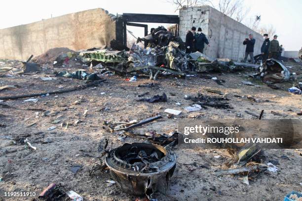 People and rescue teams are pictured amid the wreckage after a Ukrainian plane carrying 176 passengers crashed near Imam Khomeini airport in the...