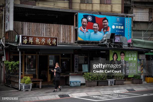 Woman walks past campaign posters for the ruling Democratic Progressive Party and the Kuomintang Party ahead of Saturdays presidential election, on...