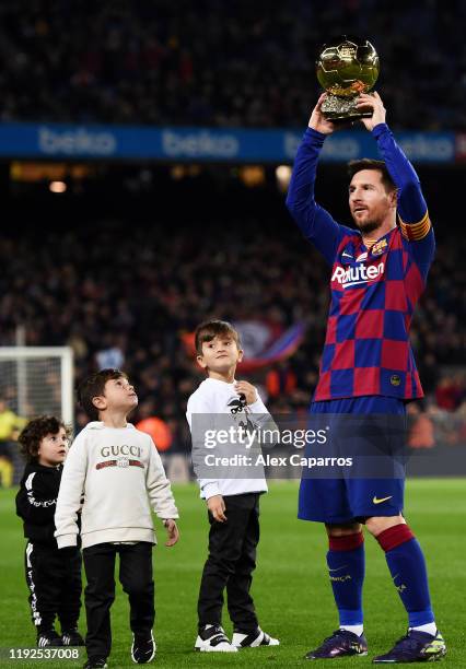 Lionel Messi of FC Barcelona lifts up his sixth Ballon d'Or trophy as his children Ciro Messi Roccuzzo, Thiago Messi Roccuzzo and Mateo Messi...