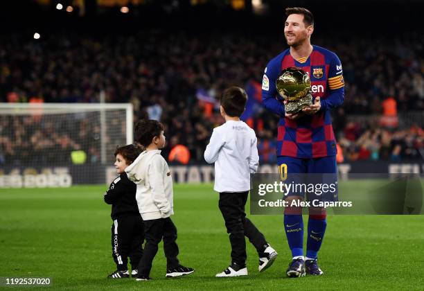 Lionel Messi of FC Barcelona lifts up his sixth Ballon d'Or trophy as his children Ciro Messi Roccuzzo, Thiago Messi Roccuzzo and Mateo Messi...