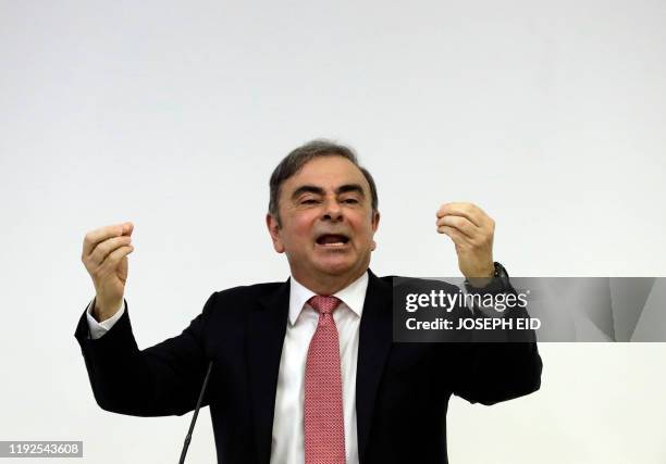 Former Renault-Nissan boss Carlos Ghosn raises his hands as he addresses a large crowd of journalists on his reasons for dodging trial in Japan,...