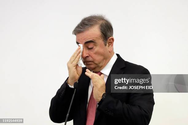 Former Renault-Nissan boss Carlos Ghosn wipes his right eye with a tissue as he addresses a large crowd of journalists on his reasons for dodging...