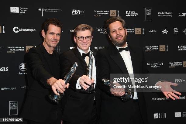 Achim von Borries, Henk Handloegten and Tom Tykwer pose with the European Achievement in Fiction Series Award at the 32nd European Film Awards at...