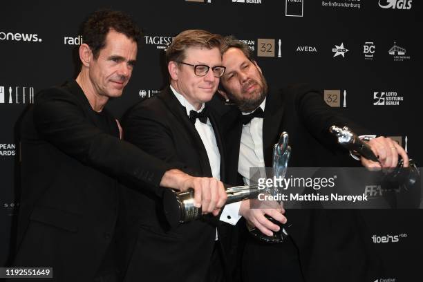 Achim von Borries, Henk Handloegten and Tom Tykwer pose with the European Achievement in Fiction Series Award at the 32nd European Film Awards at...
