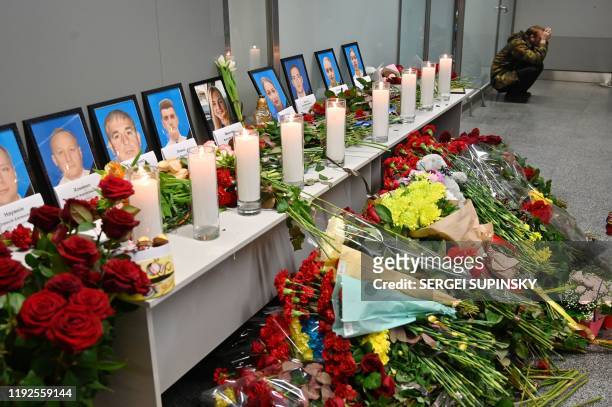 Man sits by a memorial for the victims of the Ukraine International Airlines Boeing 737-800 crash in the Iranian capital Tehran, at the Boryspil...