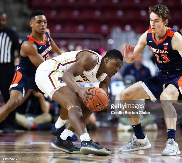 Boston College Eagles' Jairus Hamilton, center, tries to hold on to the ball between Virginia's Casey Morsell, left. And Kody Stattmann, right, in...
