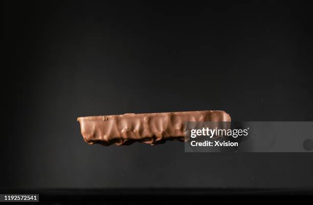 chocolate protein energy bar candy flying in mid air captured with high speed sync."n - nougat stock-fotos und bilder