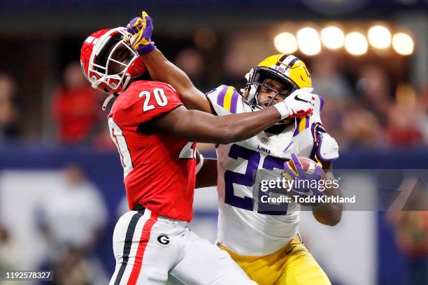 Clyde Edwards-Helaire of the LSU Tigers stiff arms J.R. Reed of the Georgia Bulldogs in the second half during the SEC Championship game at...