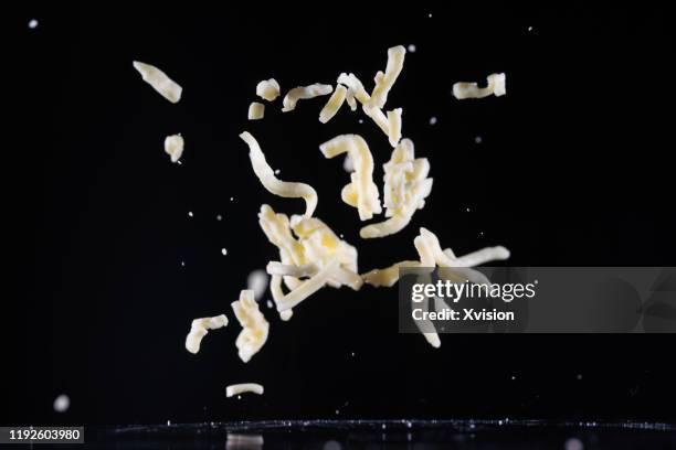 mozzarella cheese shred flying in mid air captured with high speed sync."n - gerieben stock-fotos und bilder
