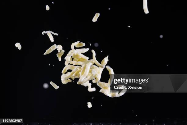 mozzarella cheese shred flying in mid air captured with high speed sync."n - grated stock pictures, royalty-free photos & images